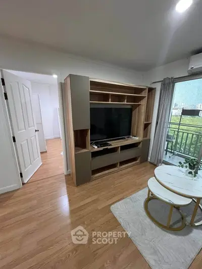 Modern living room with wooden flooring, stylish TV unit, and balcony view in a contemporary apartment.