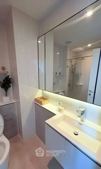 Modern bathroom with sleek fixtures and large mirror in contemporary apartment.