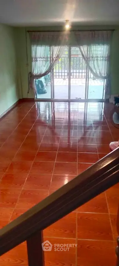 Spacious living room with glossy wooden flooring and large windows leading to a balcony.