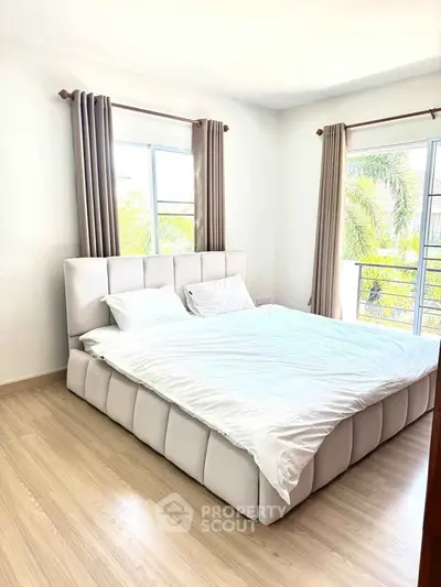 Bright and airy bedroom with large windows and modern decor, perfect for relaxation.