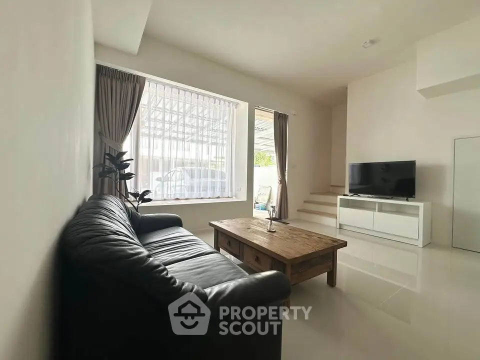 Spacious living room with modern decor, large window, and sleek furniture in a bright home.