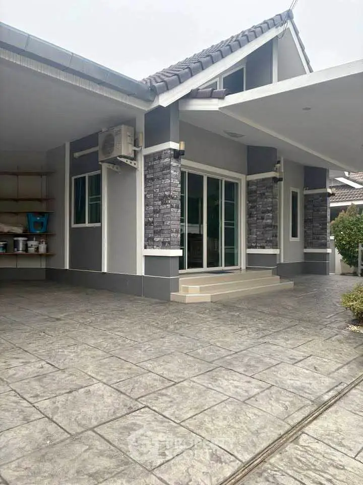 Modern single-story house with stylish stone facade and spacious driveway.