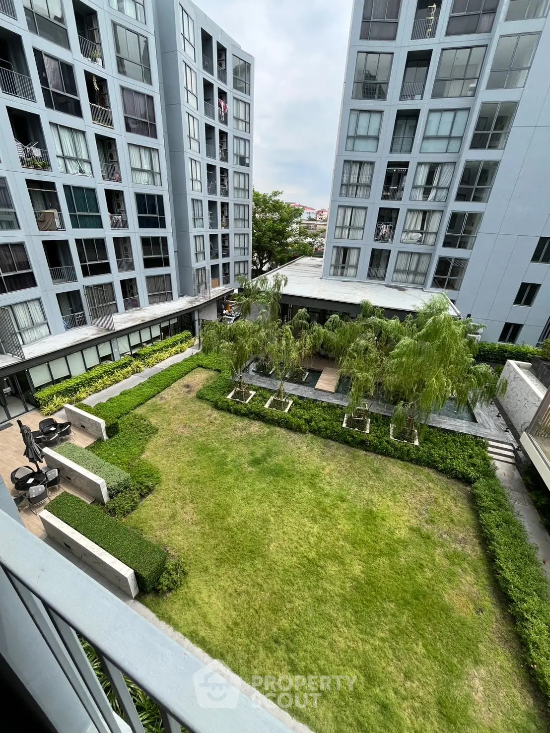 Modern apartment complex with lush green courtyard and contemporary architecture.