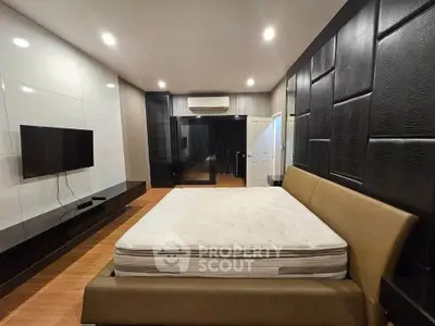 Luxurious modern bedroom with sleek design and spacious layout, featuring a large bed and wall-mounted TV.