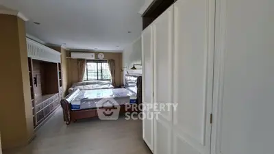 Spacious bedroom with elegant furnishings and large window for natural light.