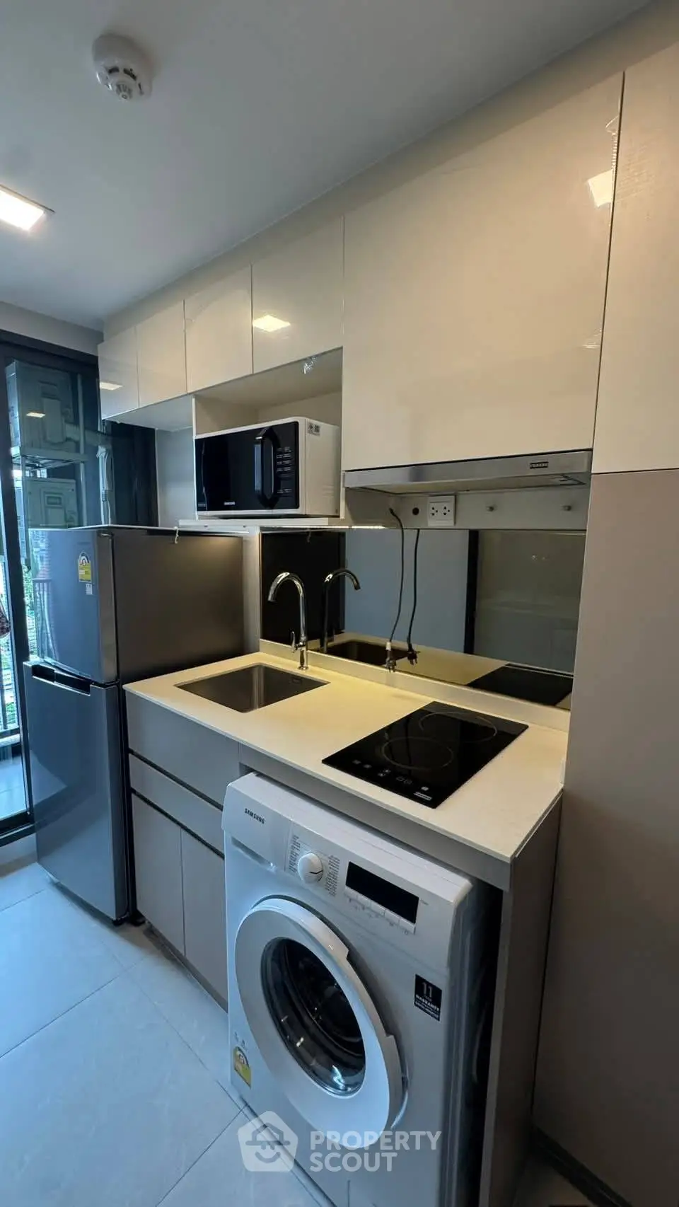 Modern kitchen with sleek appliances and washing machine in compact layout