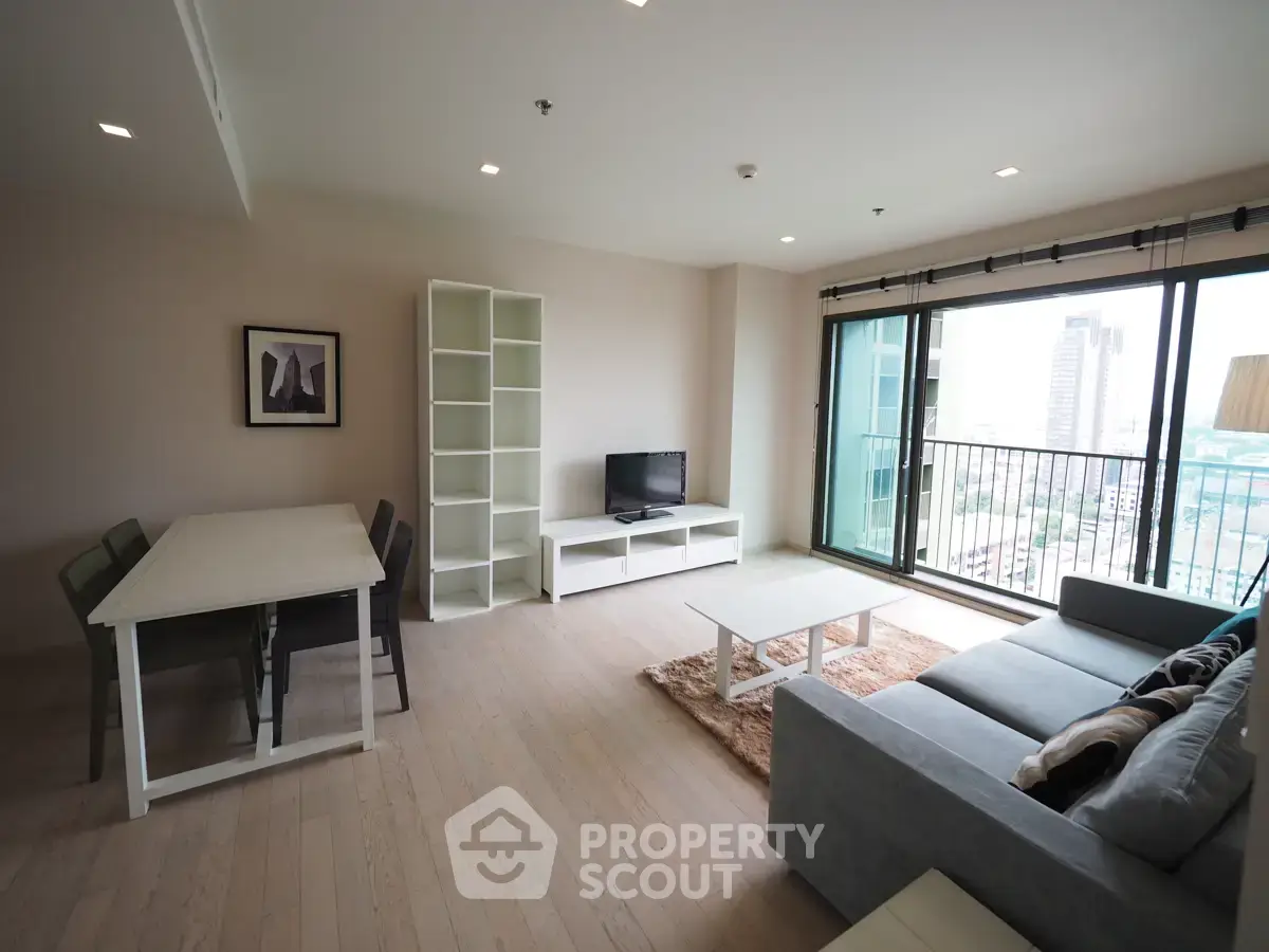 Spacious modern living room with large windows and city view, featuring stylish furniture and open layout.