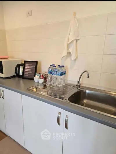 Modern kitchen with sleek countertop, stainless steel sink, and essential appliances for convenient living.