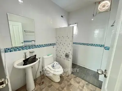 Modern bathroom with pedestal sink and tiled shower area in a bright, clean space.