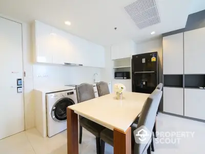 Modern kitchen with dining area and built-in appliances in a sleek apartment.