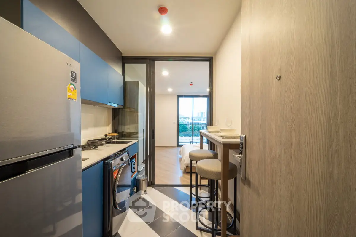 Modern kitchen with sleek appliances and open layout leading to a bright living area with city view.