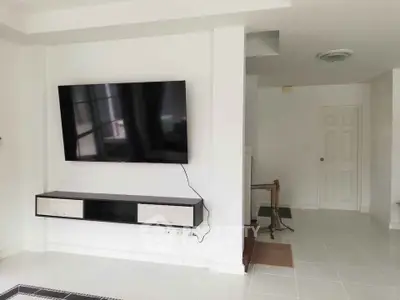 Modern living room with wall-mounted TV and sleek storage unit in a bright, minimalist design.
