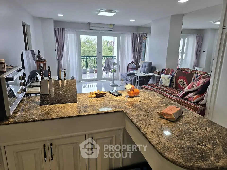 Spacious open-plan kitchen and living room with modern decor and balcony view.