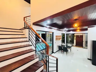 Stunning modern interior with open layout and pool view, featuring elegant staircase and stylish dining area.