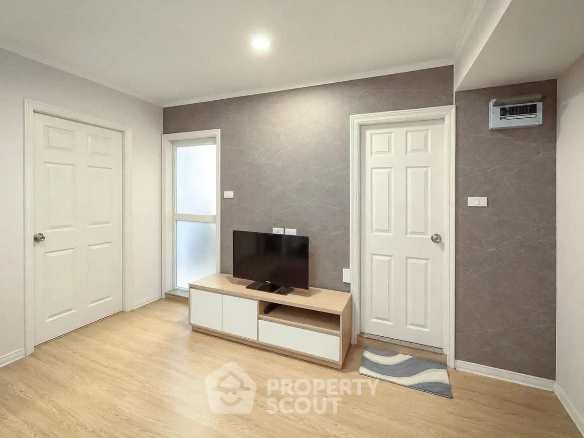Modern living room with stylish decor and wooden flooring, featuring a sleek TV stand and ambient lighting.