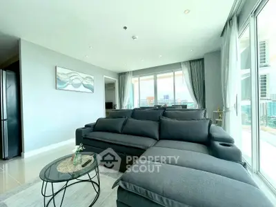 Spacious modern living room with large windows and stylish gray sofa.