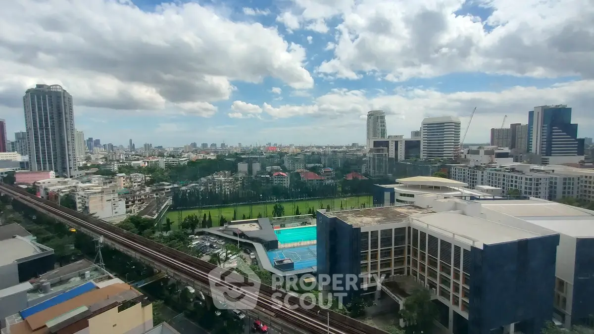 Stunning cityscape view with modern buildings and lush green sports field under a vibrant sky.