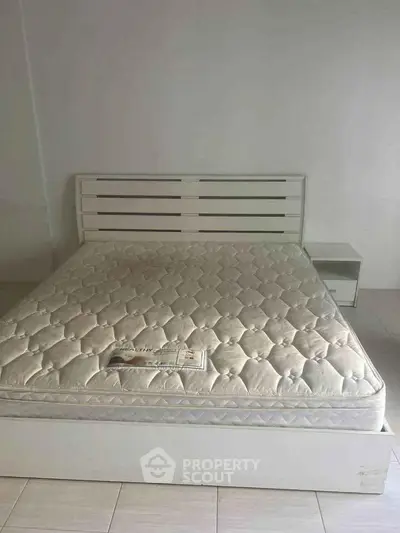 Spacious bedroom with modern bed frame and comfortable mattress in minimalist design.