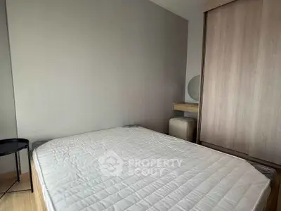 Modern bedroom with minimalist design featuring a comfortable bed and sleek wooden wardrobe.