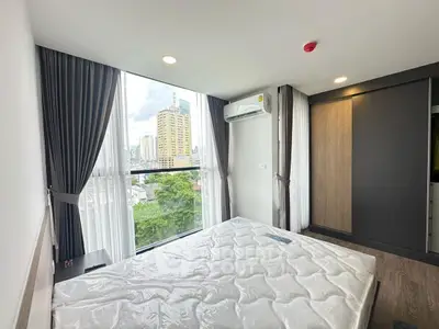 Modern bedroom with large window offering city view, featuring sleek design and ample natural light.