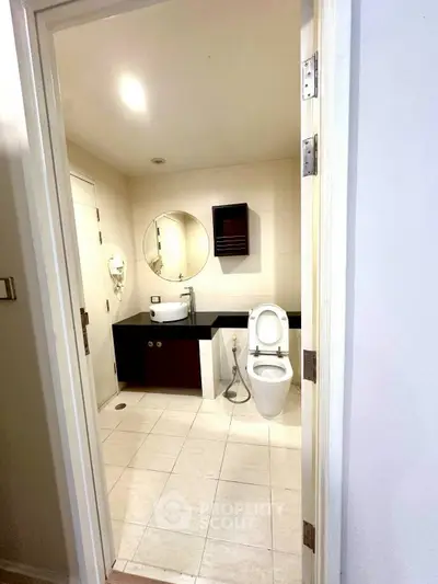 Modern bathroom with sleek fixtures and round mirror in a bright setting.