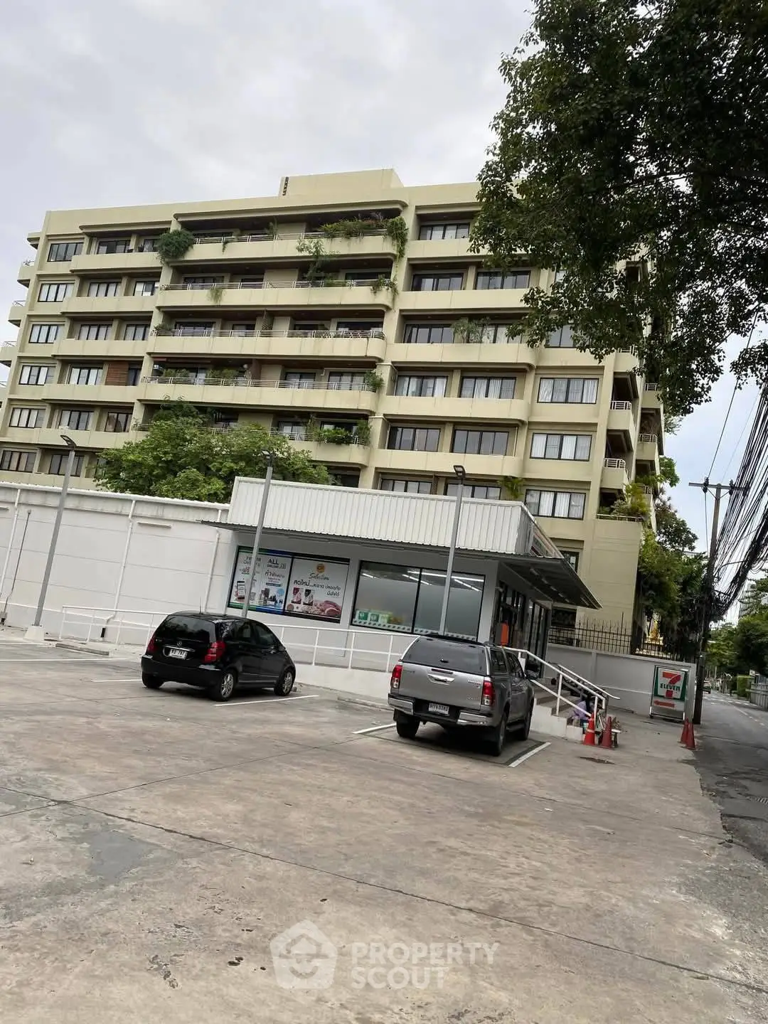 Modern apartment building with parking area and lush greenery, ideal urban living.