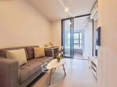Modern living room with cozy sofa and glass partition leading to bedroom