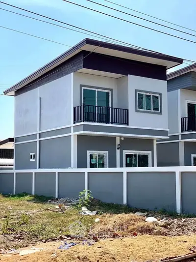 Modern two-story house with balcony and sleek design in suburban area.