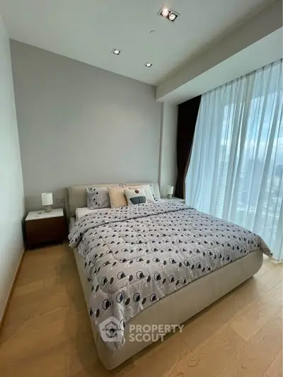 Spacious bedroom with modern decor and large window offering city views.