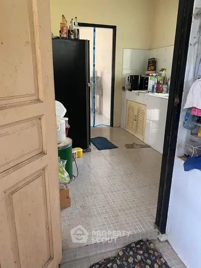 Cozy kitchen with tiled floor and black fridge, featuring a compact layout and essential appliances.