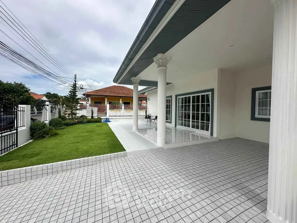 Elegant exterior view of a modern home with spacious patio and lush green lawn, perfect for outdoor living.
