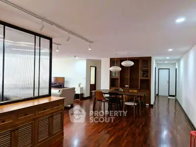 Spacious open-plan living and dining area with modern decor and wooden flooring.