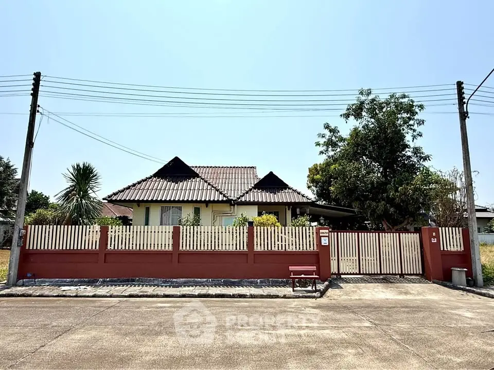 Charming single-story house with red fence and lush greenery, perfect for serene living.