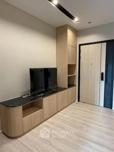 Modern living room with sleek wooden cabinetry and flat-screen TV, showcasing minimalist design.