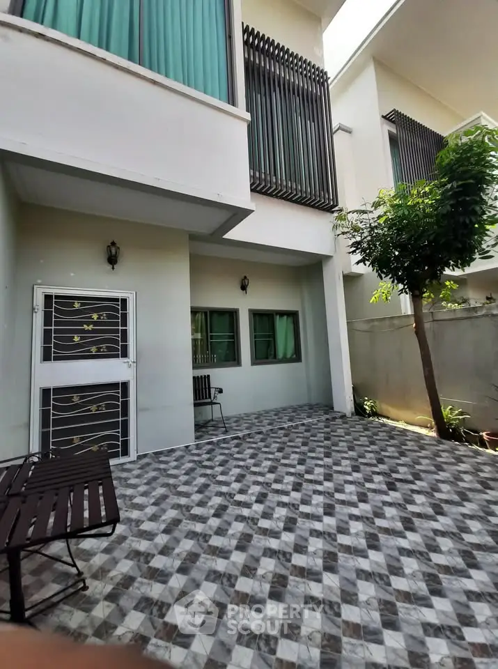Modern residential exterior with stylish facade and spacious tiled patio area.