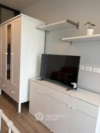 Modern living room with sleek TV stand, wardrobe, and floating shelves in a stylish apartment.