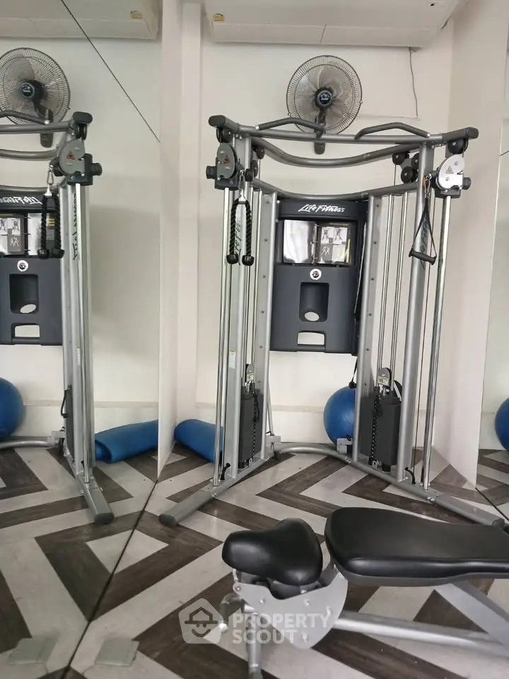Modern gym with fitness equipment and mirrored walls in a stylish real estate property.