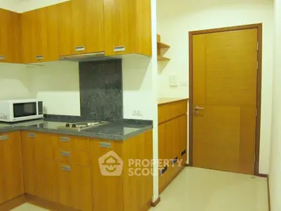 Modern kitchen with wooden cabinets and sleek appliances in a cozy apartment.