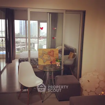 Modern apartment with glass partition, cozy seating, and city view from the bedroom.