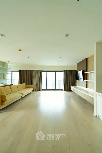 Spacious modern living room with large windows and elegant wooden flooring.