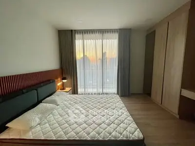 Modern bedroom with large window and sunset view, featuring sleek design and cozy ambiance.