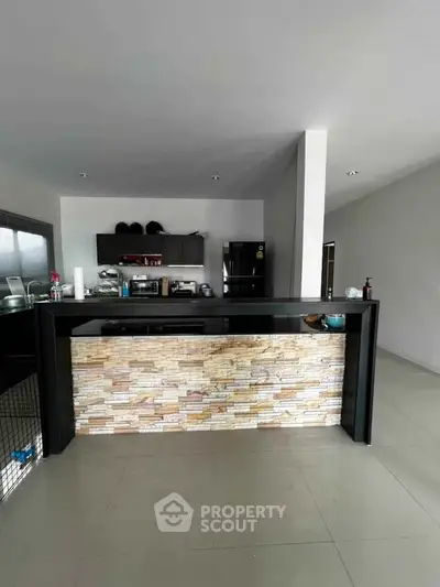 Modern kitchen with sleek black cabinetry and stone accent island, perfect for culinary enthusiasts.