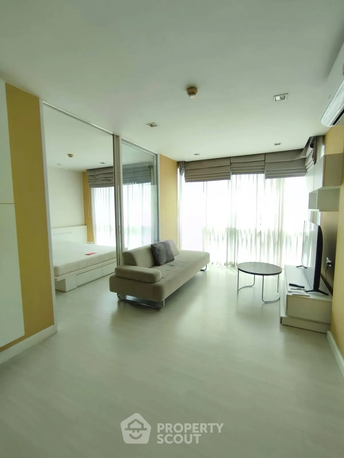 Modern living room with large windows and natural light, featuring a sleek sofa and minimalist decor.
