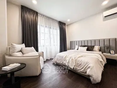 Elegant bedroom with cozy bed and stylish armchair, featuring modern decor and soft lighting.
