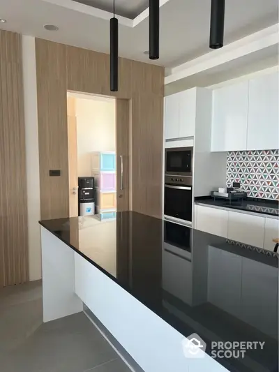 Modern kitchen with sleek black countertop and built-in oven in stylish apartment