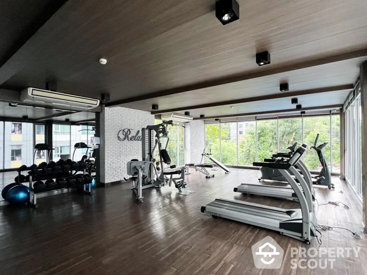 Spacious modern gym with large windows and fitness equipment in a residential building.