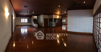 Spacious wooden-floored interior with elegant lighting and large windows.