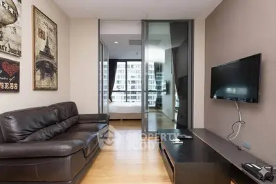 Modern living room with leather sofa and wall-mounted TV, leading to a bedroom with city view.