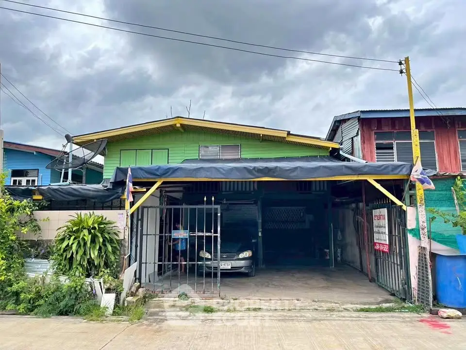 Charming two-story house with carport under cloudy skies, perfect for family living.