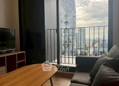 Modern living room with balcony view of city skyline and iconic building.